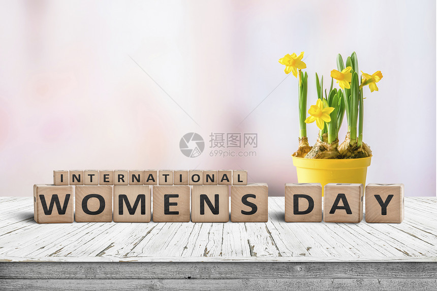 国际妇女节标志与黄色水仙花木桌上与粉红色背景图片