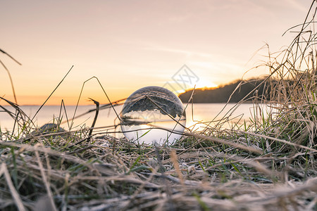 水晶球寒冷的天,清晨日出的湖边,冰封的草地上图片