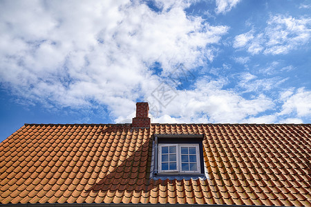 夏天,蓝天下,用屋顶窗户个小烟囱铺上红色的屋顶图片