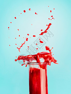 杯红色飞溅的夏季饮料冰沙果汁站蓝色背景为您的,食谱文字健康饮料的图片