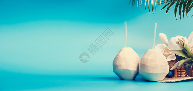 夏季热带度假背景横幅与新鲜的热带椰子鸡尾酒,喝吸管棕榈叶花站蓝色绿松石背景旅行假期背景图片
