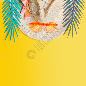 带橙色太阳镜的草帽黄色背景的热带树叶,俯视图暑假热带度假平躺图片