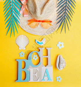 夏季海滩配件带太阳镜的草帽,海壳黄色背景的热带树叶,俯视图暑假热带度假平躺背景图片