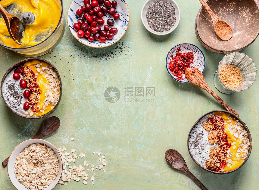 健康的冰沙碗背景早餐芒果冰沙碗准备椰子壳与顶部燕麦片,辣椒种子,浆果坚果夏季健康饮食的风景图片