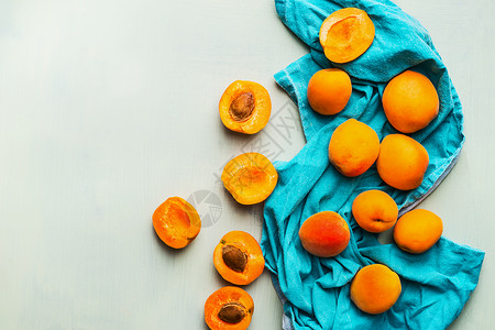 新鲜成熟的杏花蓝色餐巾纸上,淡淡的薄荷背景下,顶部观看季节水果的收获健康干净的饮食观念背景图片