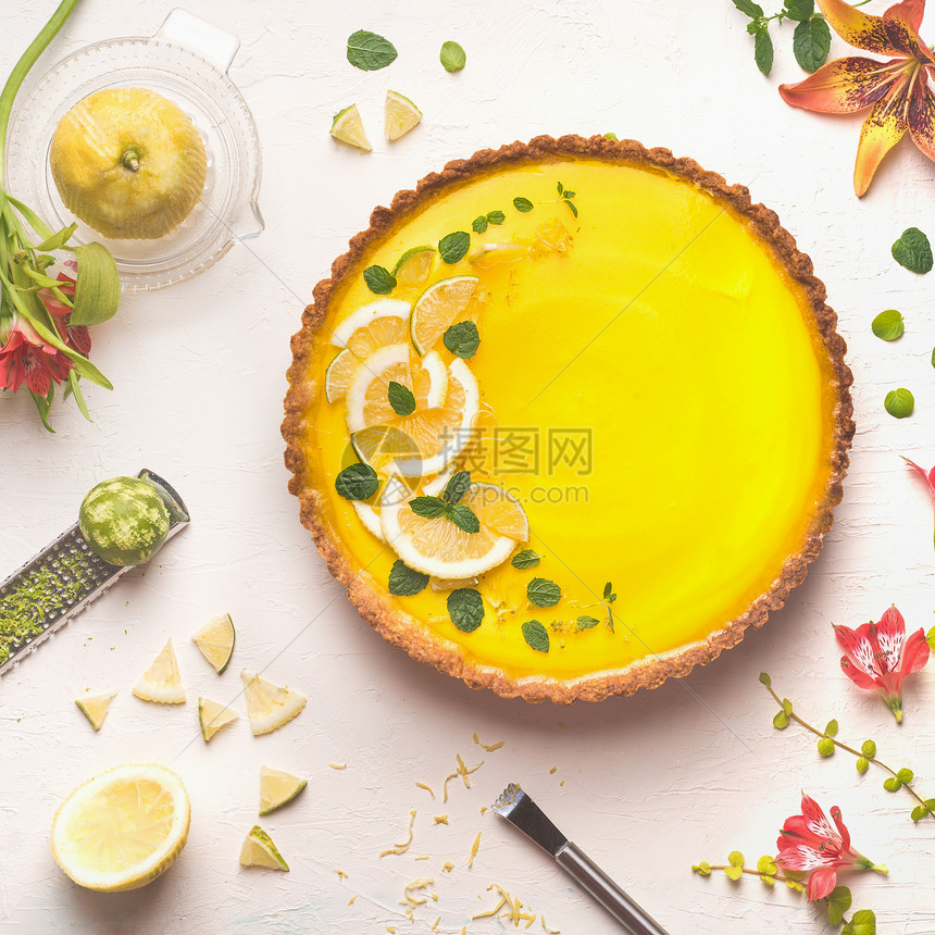黄色柠檬馅饼,顶部新鲜柠檬石灰片,白色桌子背景上柑橘成分鲜花,顶部景色传统的法国菜图片