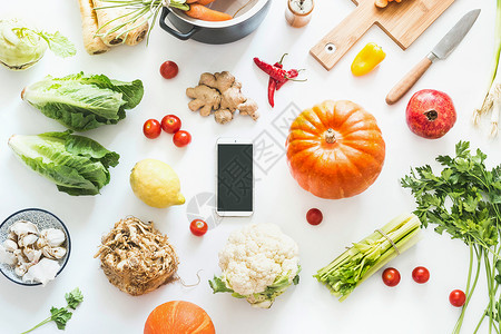 食谱设计秋季烹饪平板躺智能手机与空白屏幕各种季节秋季蔬菜配料南瓜白色桌背景,顶部视图舒适的家秋收食物博客背景