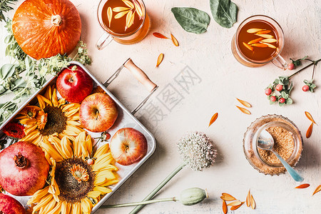 秋夏末与向日葵,南瓜,苹果,花草药茶白色桌上的杯子成的风景框架图片