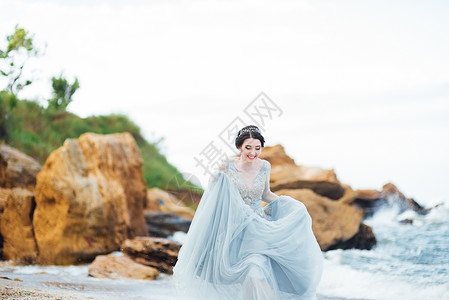 新娘穿着件蓝色的浅色连衣裙,沿着海洋行走图片