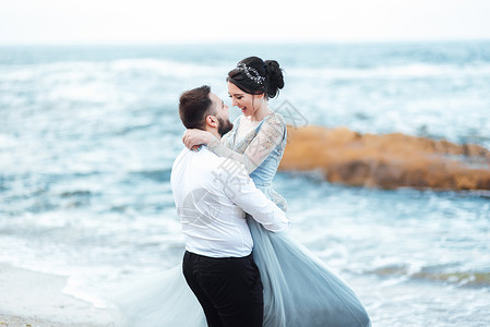同层排水同夫妇位穿着蓝色连衣裙的新娘沿着海边散步背景