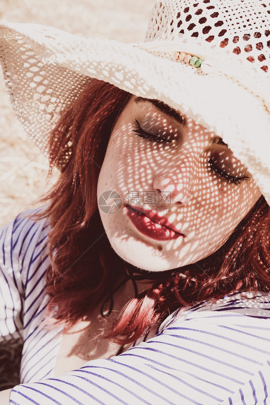 红头发的模特夏天戴着帽子保护自己免受阳光的伤害图片