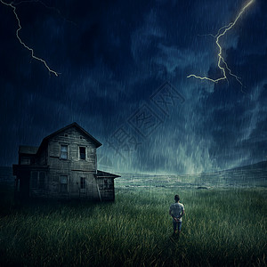 幽灵般的风景,就像个小男孩草地上散步样,看着黑暗的暴风雨天空下的鬼屋图片