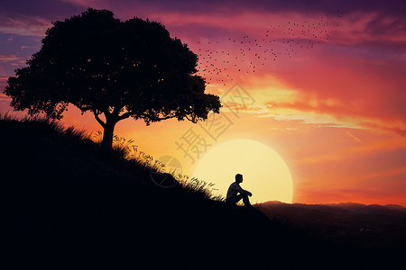 男孩独自坐自然中心的座小山上,日落的背景上远离人群,等待大自然的治愈力量图片