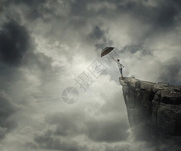男孩试图抓住他的伞悬崖边缘的云逃跑然后飞走高清图片