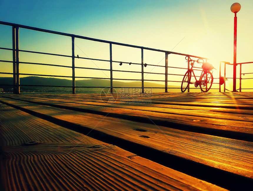 早上海边甲板上自行车的轮廓海边的金色日出保加利亚尼塞巴尔阳光海滩的生活方式背景图片