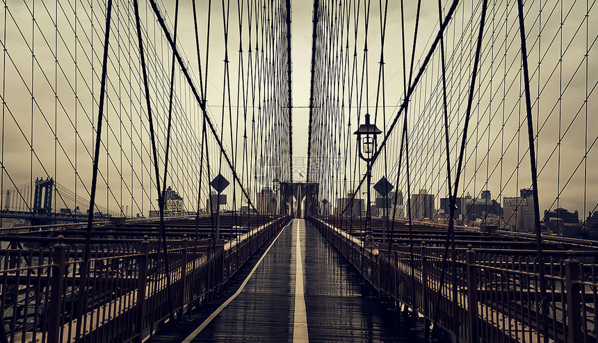 纽约市的布鲁克林大桥上,曼哈顿与哈德逊河上的摩天大楼城市天际线密切相关图片
