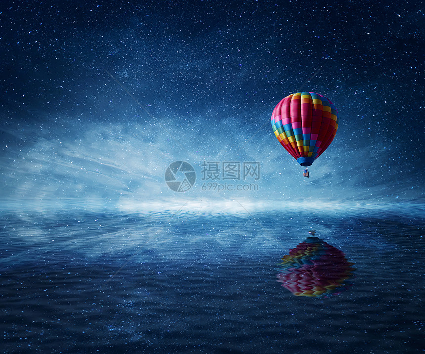 热气球飞过冰冷的深蓝色的大海美妙的景观,星空背景水反射图片