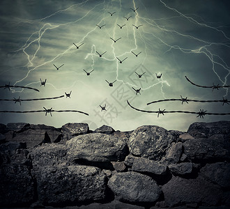 座监狱的石墙栅栏,铁丝网,闪电的天空背景上变成了飞鸟自由成功的图片
