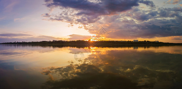 美妙的日落全景城市地平线上,个寂静的夏季傍晚,平静的湖水上倒影图片