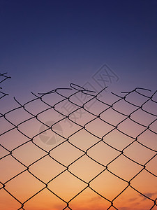 旧的铁丝网栅栏纹理日落的天空背景下图片