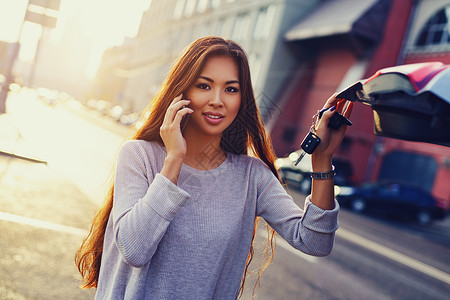 轻的亚洲商务妇女,电话站汽车上,钥匙早晨的城市背景车的亚洲女人图片
