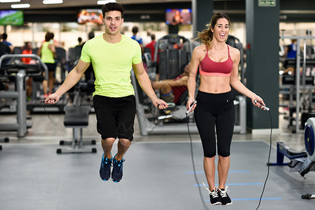 英俊的男人美丽的运动女人锻炼与跳绳交叉健身健身房图片