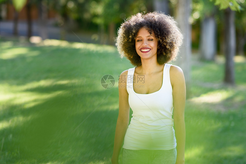轻的黑人妇女,留着AFRO发型,城市公园闭着眼睛笑着穿着休闲衣服的混合女孩图片