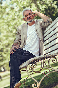 个忧郁的成熟男人坐城市公园的长凳上的肖像白发胡须的老男穿着休闲服装图片