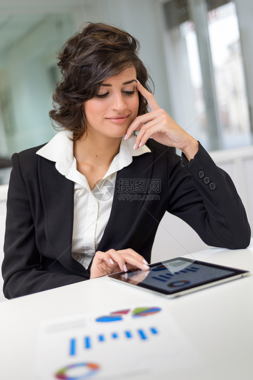 个商业女人看着她的平板电脑的肖像现代办公室的女商人图片