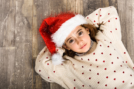 可爱的小女孩戴着诞老人的帽子躺木地板上诞节的冬天衣服图片