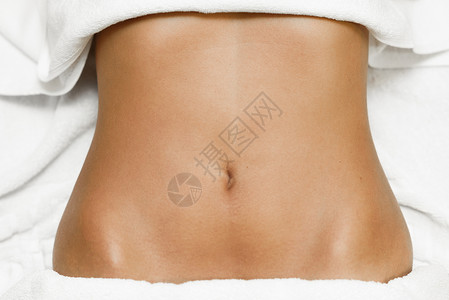 棕色女腹部的顶部视图,躺水疗床上,用白色毛巾背景图片