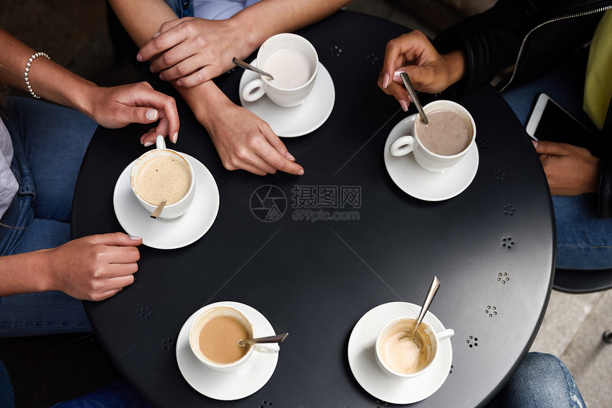 城市咖啡馆的桌子上放着咖啡杯的手的顶部视图图片