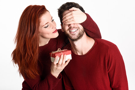 轻的女人给他的男人送礼物漂亮的夫妇穿着红色的白色背景红头发女孩图片