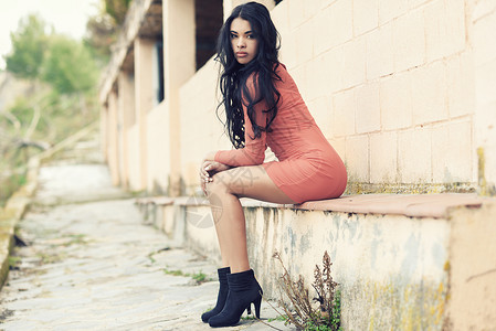 西牙裔轻女城市背景下穿着休闲橙色连衣裙的肖像图片