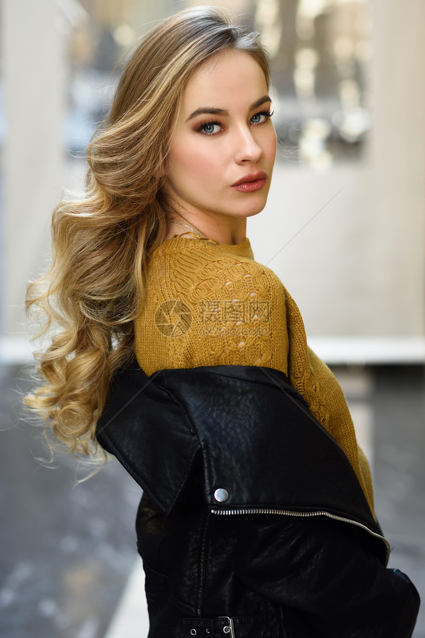 城市背景的金发女人漂亮的轻女孩穿着黑色皮夹克迷你裙站街上漂亮的俄罗斯女,留着长长的波浪发型蓝色的眼睛图片