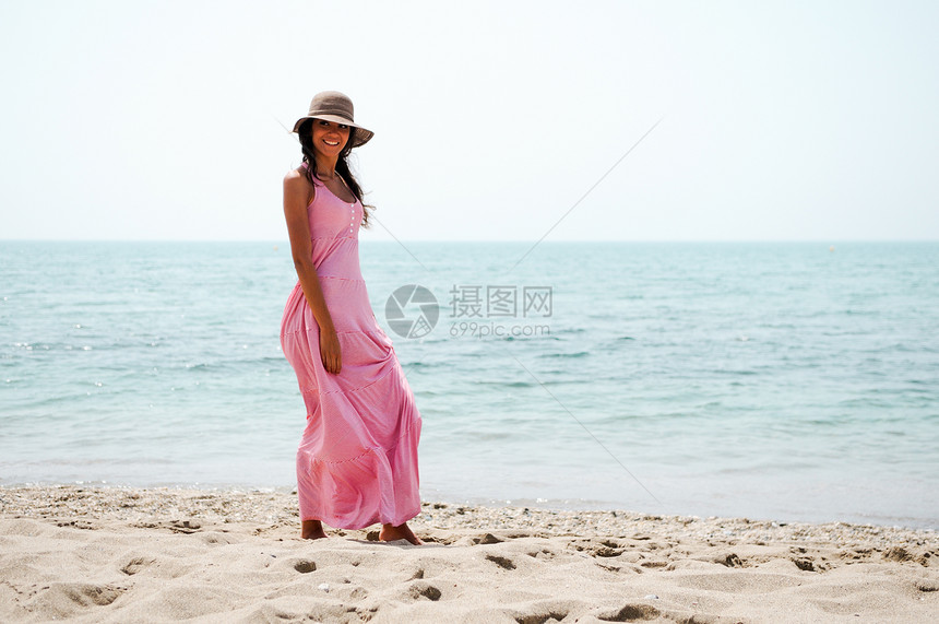 热带海滩上位穿着粉红色长裙的美女的肖像图片
