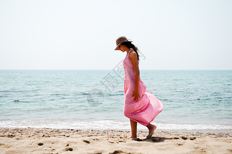热带海滩上位穿着粉红色长裙太阳帽的美女的肖像图片