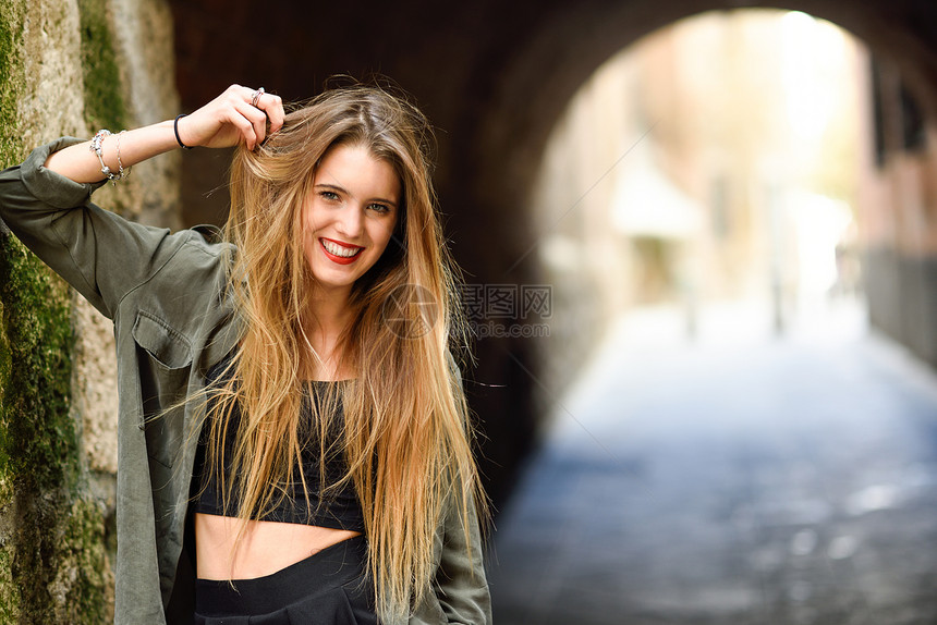 城市背景中微笑的快乐金发女孩的肖像图片