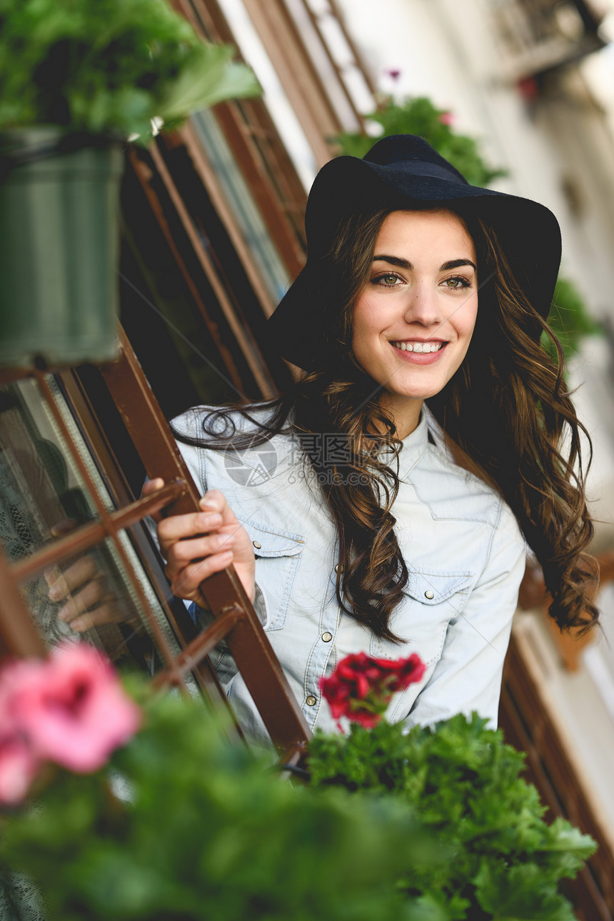 轻女子的肖像,城市背景下微笑,穿着休闲服装帽子图片