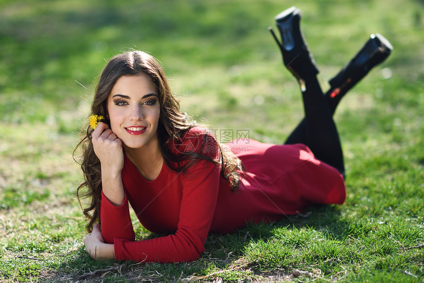 轻女人的肖像躺公园里,微笑着,头发上朵蒲公英,躺草地上图片