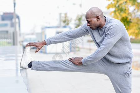黑人城市背景下跑步前伸展运动轻的男锻炼图片