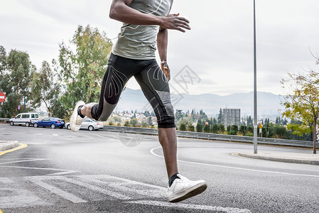 黑人城市道路上跑步,用白色耳机听音乐轻的男锻炼与城市替罪羊的背景图片