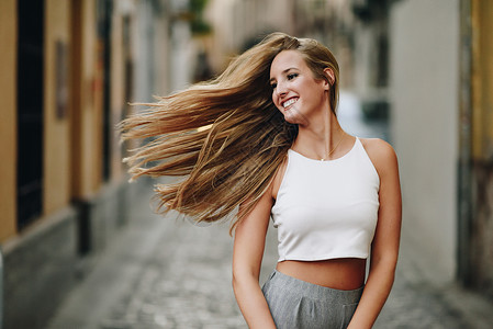 快乐的轻女人,城市背景下动人的头发金发女孩,直发型,穿着休闲服街上图片