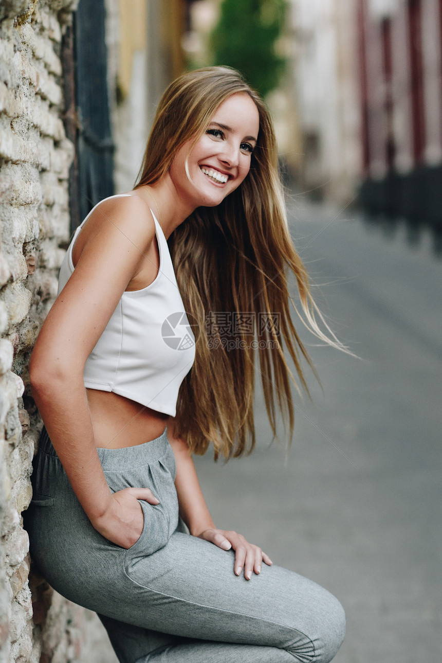 微笑的金发女孩穿着休闲服街上城市背景中直发的轻女图片