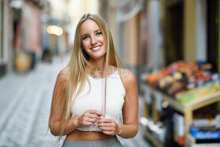 城市背景中微笑的轻女人金发女孩穿着漂亮的头发休闲服街上直发型图片