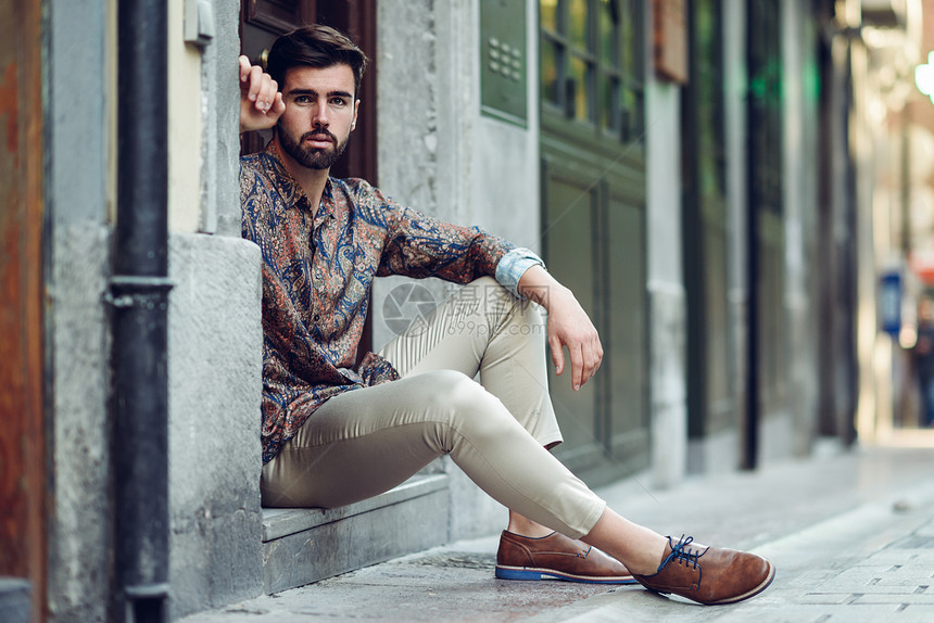 轻的留着胡子的男人,时尚的模特,坐城市的台阶上留着胡子现代发型的家伙街上看着图片