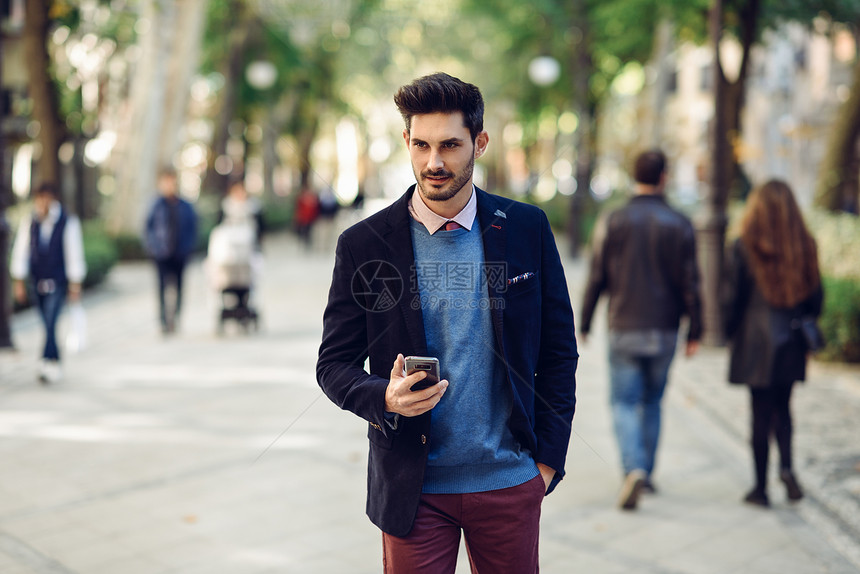 街上魅力的男人穿着英国优雅的西装,手里着智能手机轻的胡须商人,城市背景下现代发型图片
