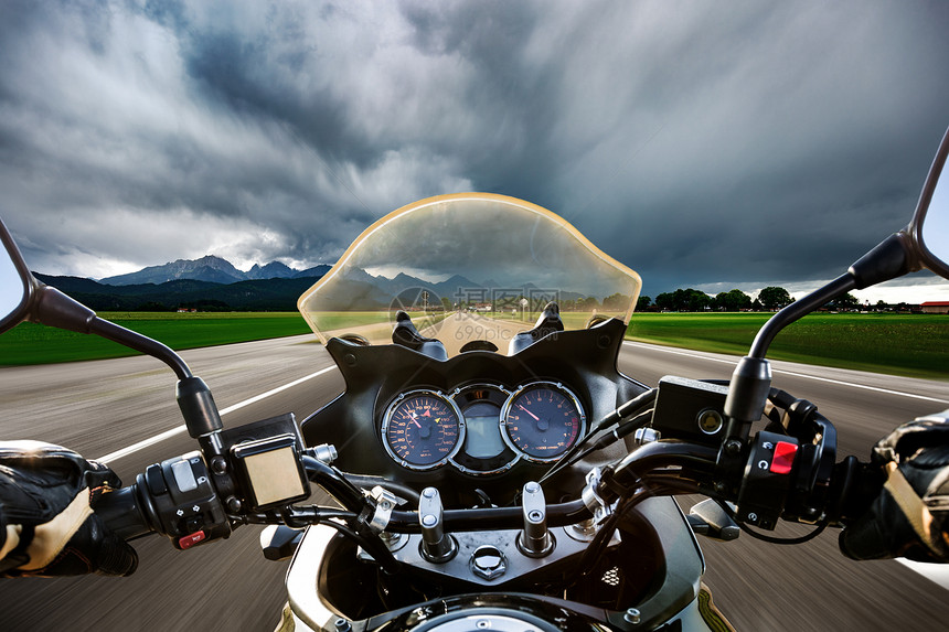 骑摩托车的自行车场闪电风暴中沿着道路飞驰福根塞施旺瑙,德国巴伐利亚图片