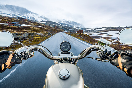开车人称自行车人称视图,挪威的山口骑摩托车的人骑着摩托车滑溜溜的路上穿过挪威的个山口围绕着雾雪人称视图背景