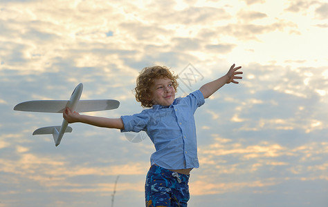 做飞机孩子小男孩田野上着个木制的飞机模型背景